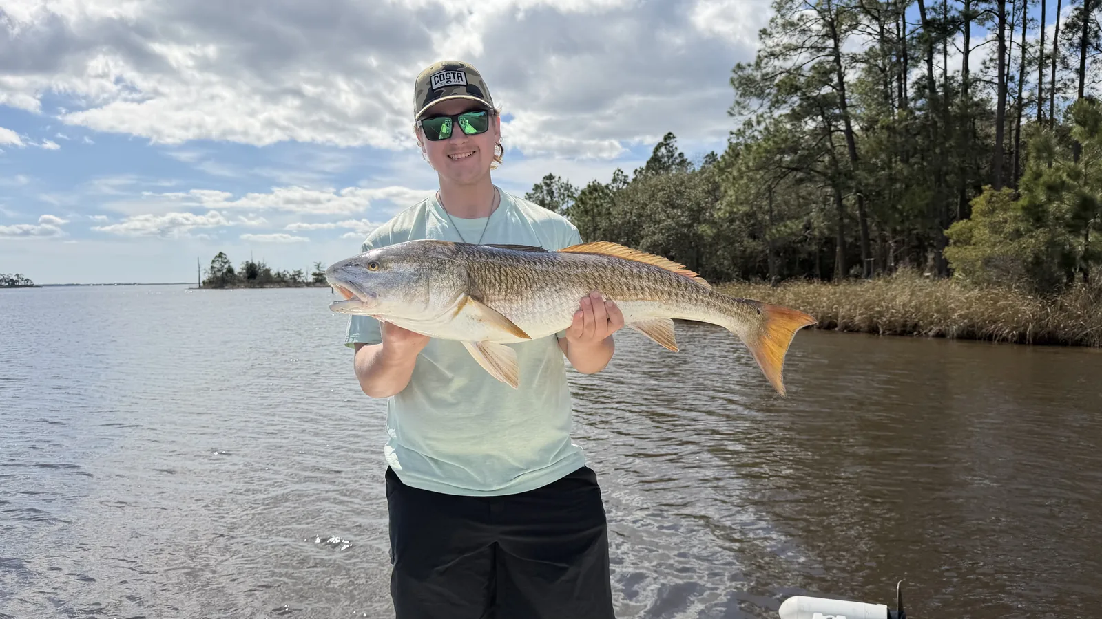 Angler holding large redfish at Black Creek