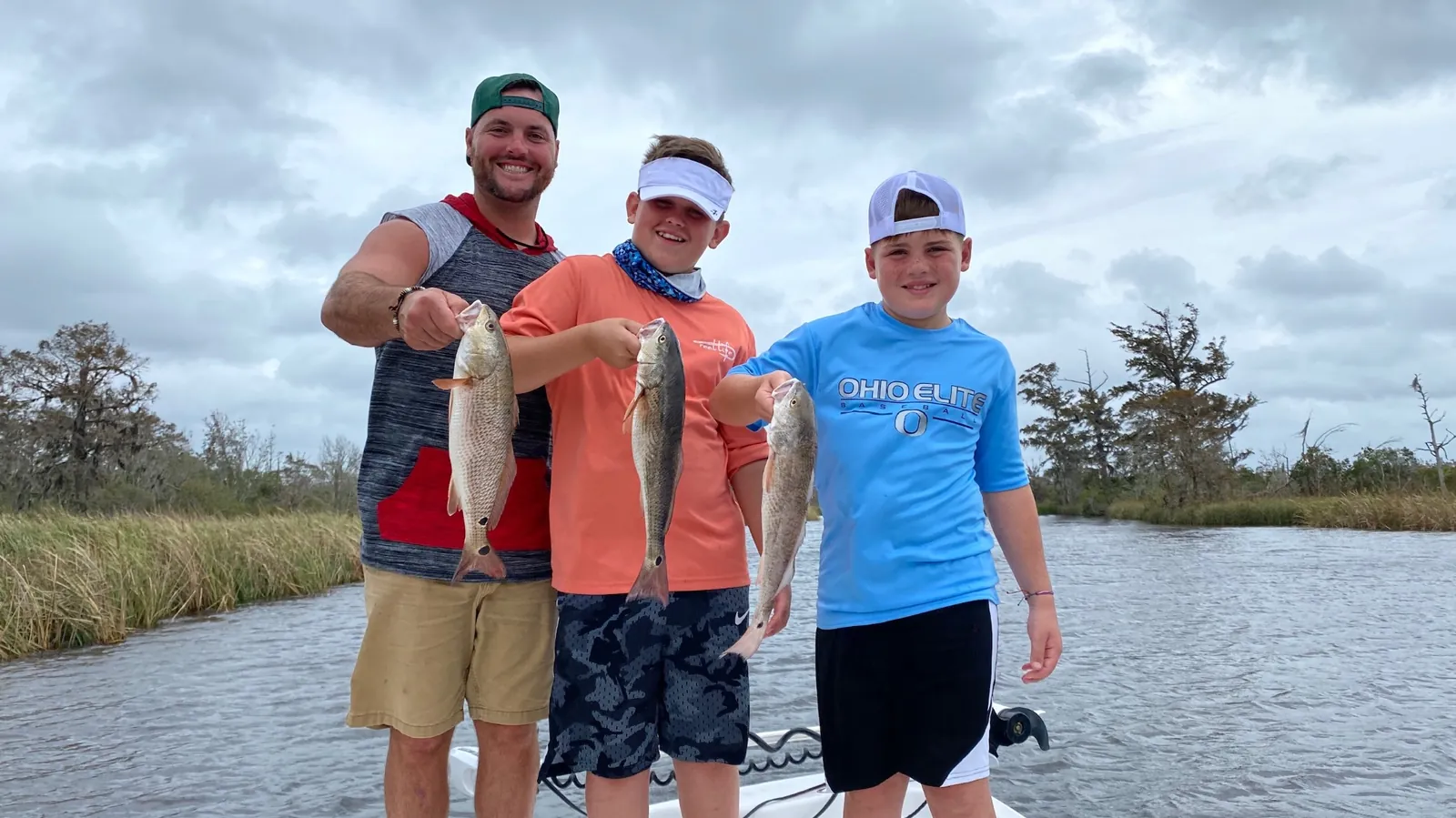 Dad and two kids holding redfish on Black Creek family charter