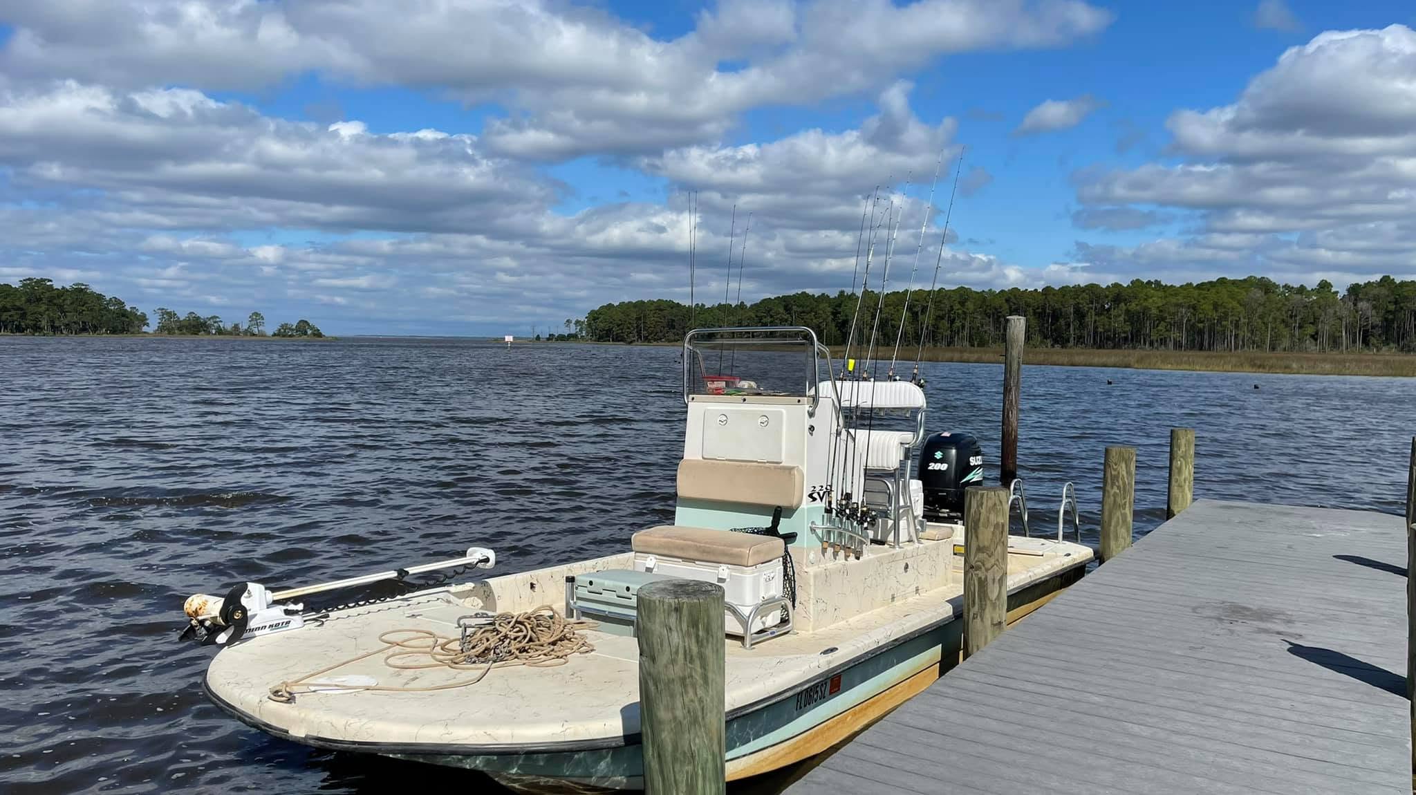 Fishing boat docked at a wooden pier on a cloudy day.