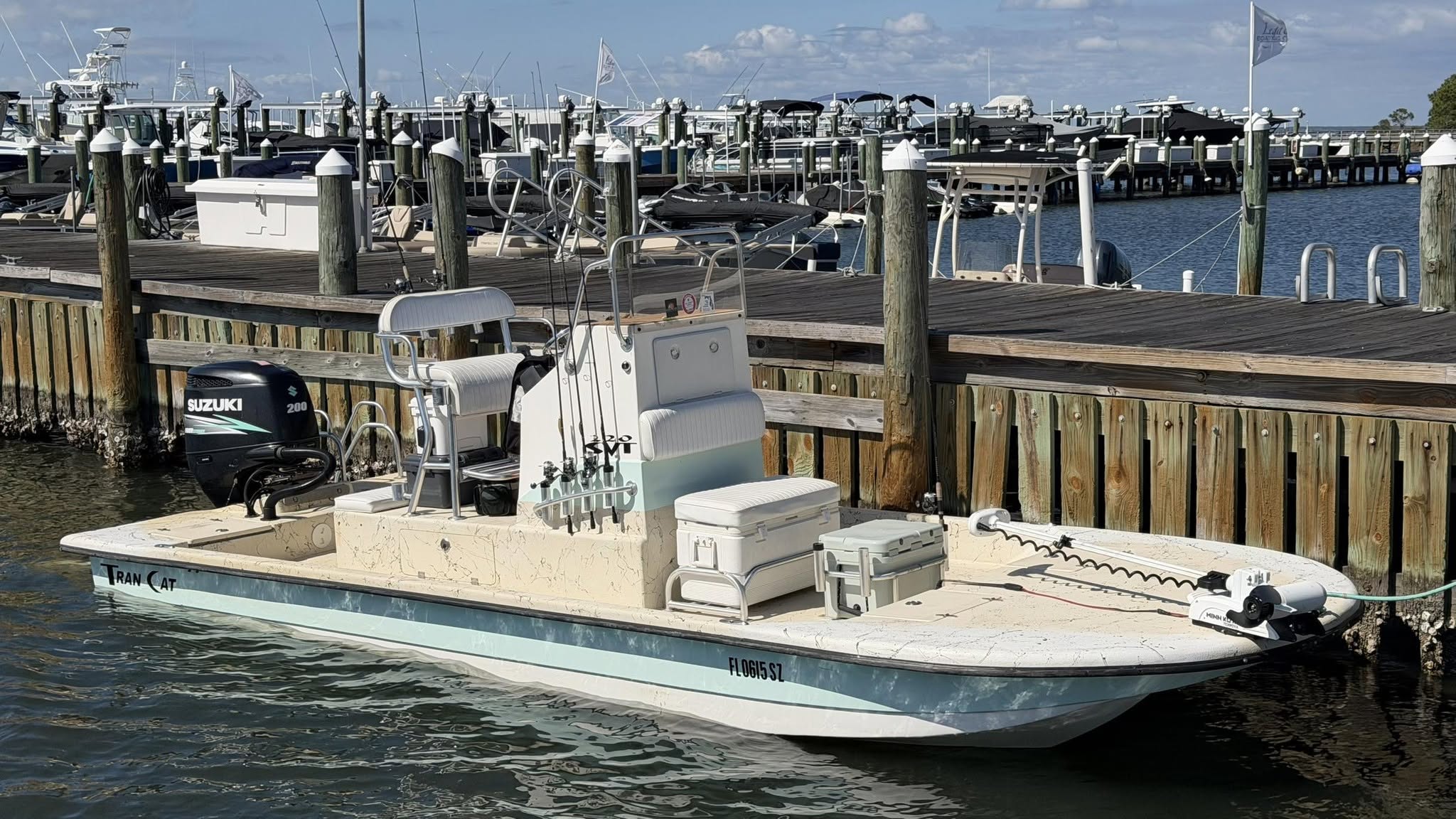 Small motorboat docked at a marina with fishing equipment.