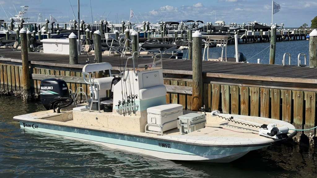 Small motorboat docked at a marina with fishing equipment.